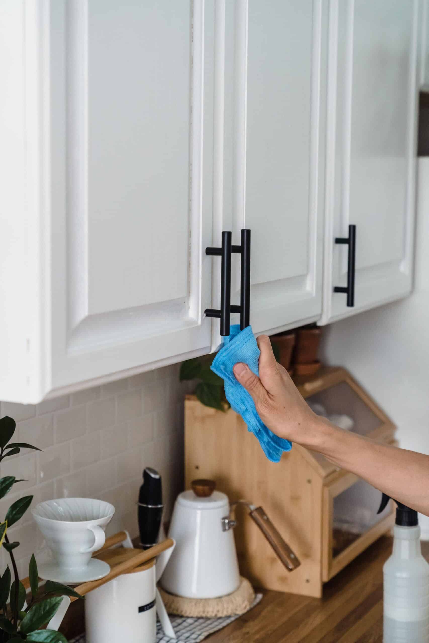 Wiping kitchen cabinets with a microfiber cloth